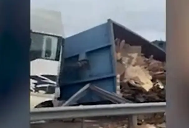 Uz Dienvidu tilta apgāzusies kravas automašīnas piekabe ar koka dēļu atgriezumiem